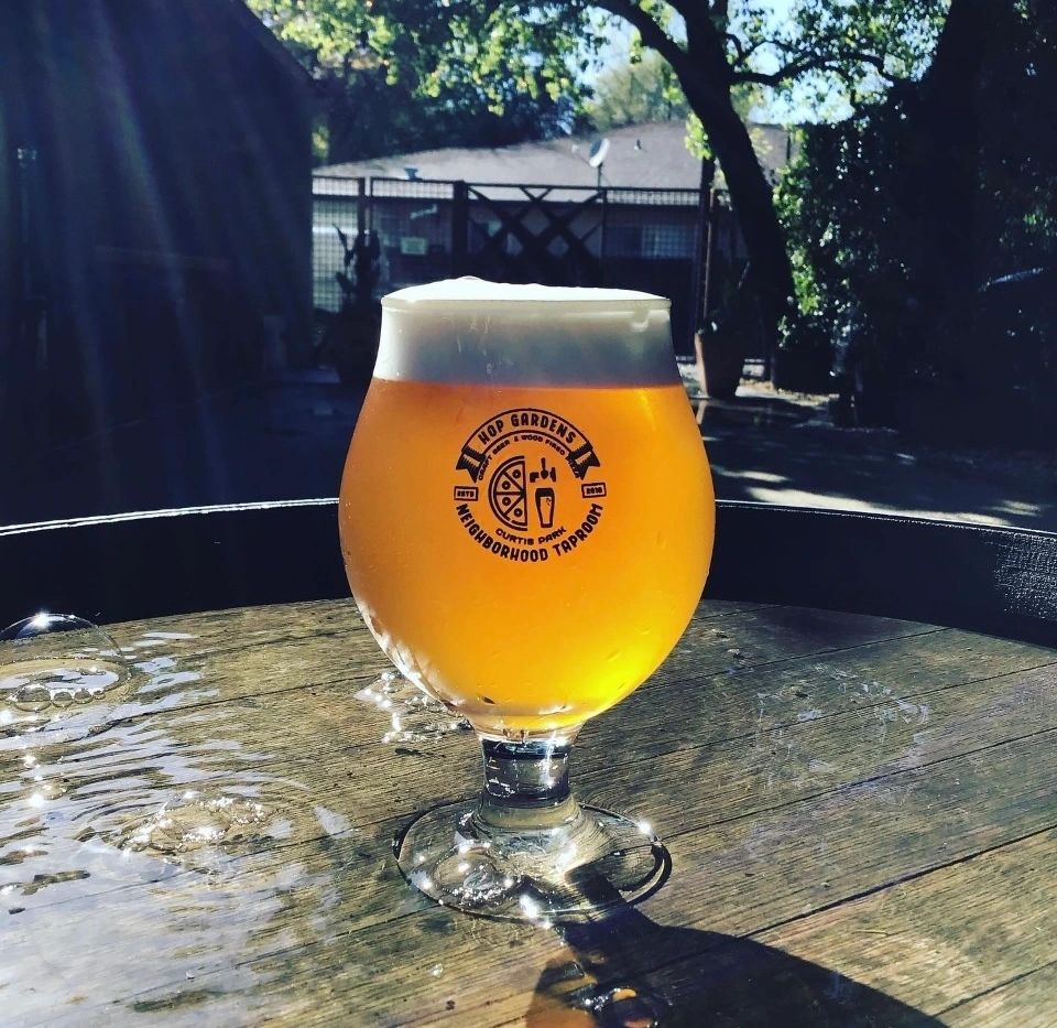 A glass of beer sitting on top of a wooden table.